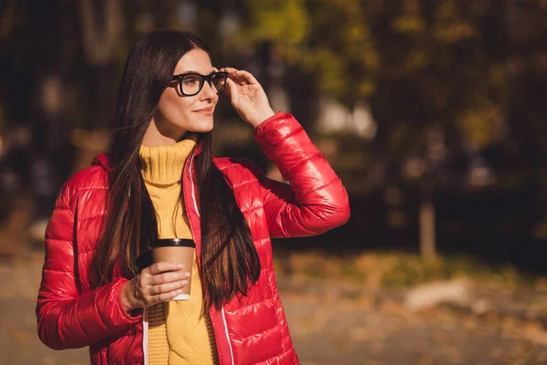 Profile side photo of trend modern girl enjoy october fall park stroll walk hold drink cappuccino takeout coffee buy barista look copyspace wear red outerwear — 스톡 사진