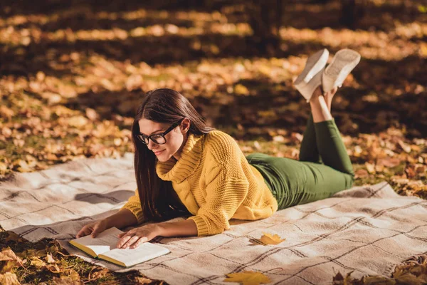 Полная длина профиля боковой фото позитивного отдыха девушки расслабиться лужайка осенний парк лежал клетчатый клетчатый одеяло читать книгу носить желтый цвет свитер — стоковое фото