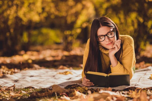 Фото положительного отдыха девушки на лужайке осеннего лесного парка лежа клетчатое одеяло читать интересную книгу носить желтый цвет пуловер — стоковое фото