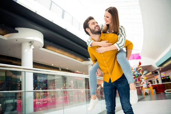 Photo de attrayant dame beau couple de gars visiter le centre commercial ensemble marchant piggyback porter pose avoir plaisir à jouer porter casual jeans chemise tenue à l'intérieur — Photo