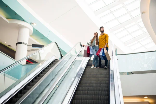 Foto de corpo inteiro da adorável senhora bonito cara casal gastar tempo livre shopping shopping abraço transportar muitos sacos movendo-se para baixo escada rolante bom humor desgaste casual jeans camisa calçado roupa dentro de casa — Fotografia de Stock