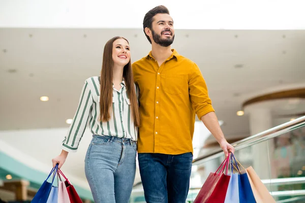 Porträt positiver fröhlicher Ehepartner Mann Frau Frau Ehemann genießen Spaß Freizeit in Einkaufszentrum Mall halten viele Pakete Taschen tragen gestreifte gelbe Hemd Jeans — Stockfoto