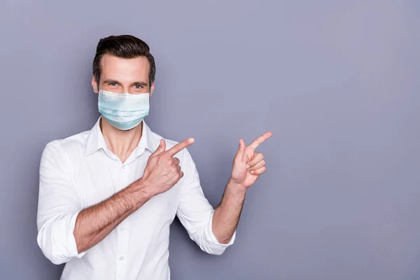 Portret van zijn hij aantrekkelijke gezonde man dragen veiligheidsgaas masker demonstreren kopieerruimte plakkaat poster stoppen infectie pandemie gezondheidszorg geïsoleerde grijze kleur achtergrond — Stockfoto