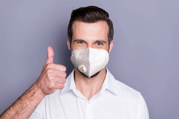 Close-up portrait of his he attractive healthy guy wearing safety n95 respirator mask showing thumbup stop influenza pandemia medicine air pollution smog solution isolated gray color background — Stock Photo, Image