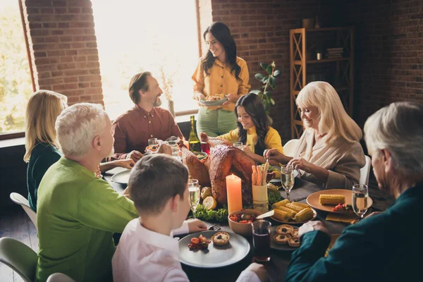 Портрет привабливих веселих сімейних батьків і бабусь і дідусів, що сидять навколо сервірованого столу, їдять домашню вечерю осінній сезон в сучасному будинку індустріального інтер'єру з цегли — стокове фото