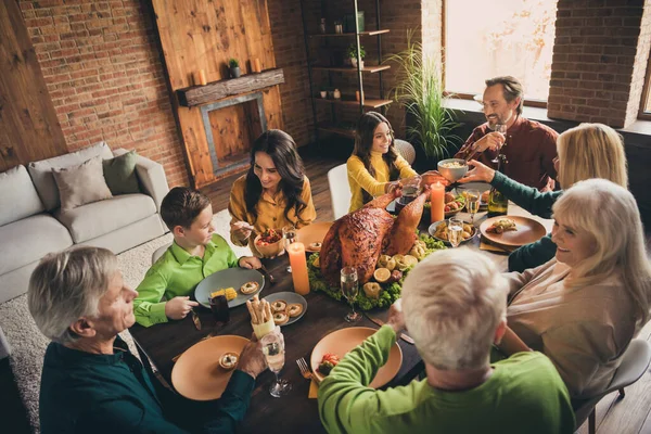 テーブルの周りに座っている素敵な魅力的な愛らしい陽気な家族の両親の祖父母の高い角度ビューの上に現代のロフトレンガ工業インテリアハウスで自家製料理を屋内で食べる — ストック写真