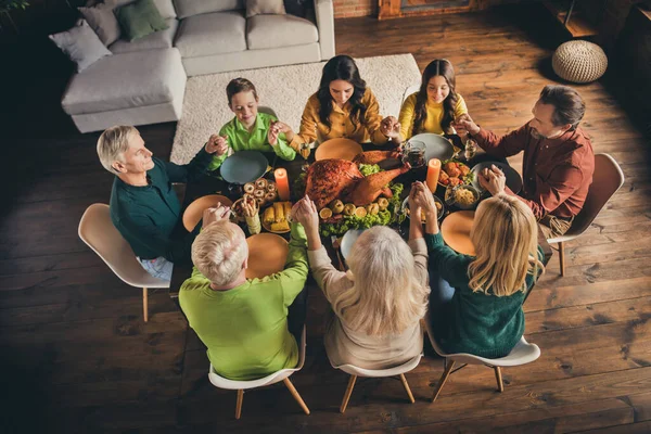 Dessus au-dessus de la vue à angle élevé de beaux beaux parents adorables grande famille complète assis autour de la table servie priant grâce occasion festale au loft moderne maison intérieure industrielle en bois à l'intérieur — Photo