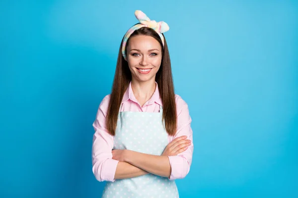 Photo of attractive pretty lady long hairdo self-confident cleaning service maid worker arms crossed toothy smiling wear headband apron pink shirt isolated blue color background — Stock Photo, Image