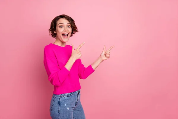 Photo of excited funny lady toothy smiling directing fingers side empty space novelty sale discount banner wear casual bright sweater jeans isolated pink pastel color background