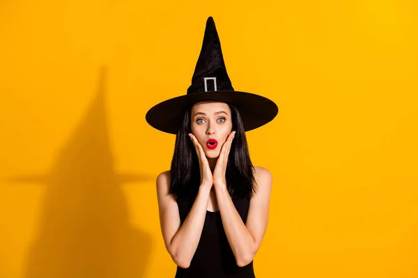 かわいい魅力的な若い魔術師の女性の写真ショックを受けた表情の手は別の女の子を参照してください同じ衣装ロールプレイイベントは黒の帽子を着用ドレス孤立明るい黄色の色の背景 — ストック写真