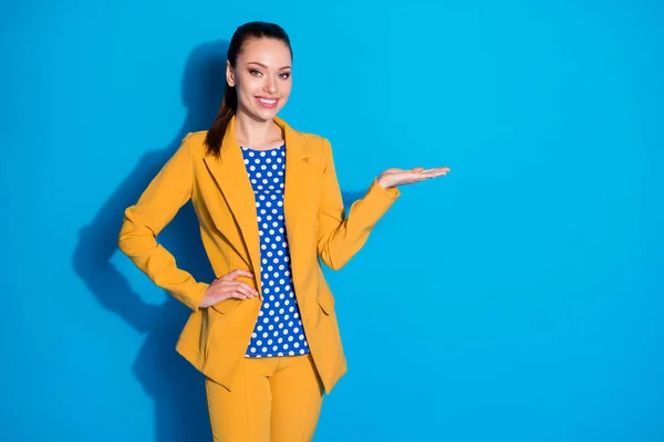 Портрет позитивной веселой девушки исполнительный представитель промоутер держать руку рекомендовать выбрать рекламу промо носить желтый пиджак брюки изолированы на синем фоне цвета — стоковое фото