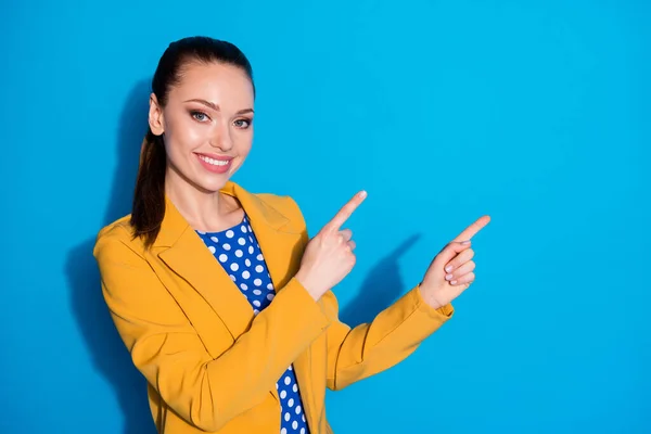 Foto van aantrekkelijke zakenvrouw succesvolle werknemer directe vingers kant lege ruimte tonen nieuwigheid product manager dragen gele blazer pak gestippelde blouse shirt geïsoleerde blauwe kleur achtergrond — Stockfoto