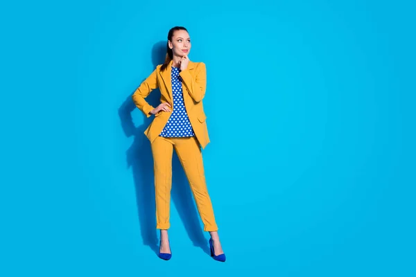 Полная длина фото привлекательный хороший работник леди смотреть сбоку пустой рукой пространство на подбородке носить желтый пиджак брюки разбросаны блузка обувь на высоких каблуках изолированы ярко-синий цвет фона — стоковое фото