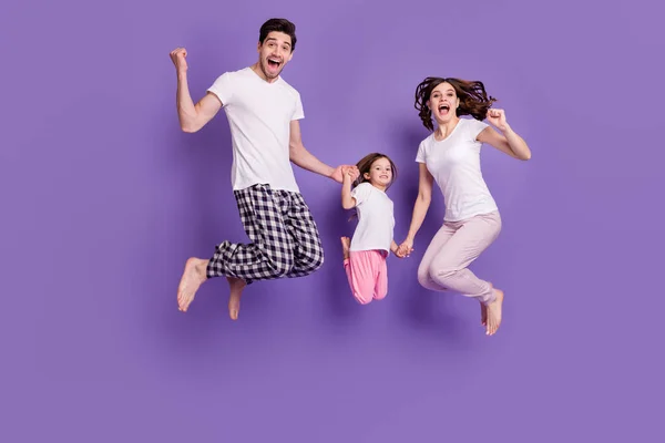 Full length body size view of nice cheerful cheery glad excited family small daughter jumping wearing pajama having fun isolated bright vivid shine vibrant violet color background — стоковое фото