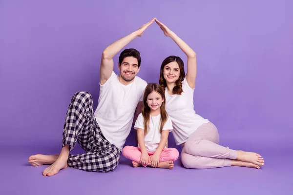 Retrato de tres personas alegre familia completa papá mamá descendencia hija usando pijama sentado mostrando techo aislado en brillante brillo vivo vibrante violeta color fondo — Foto de Stock