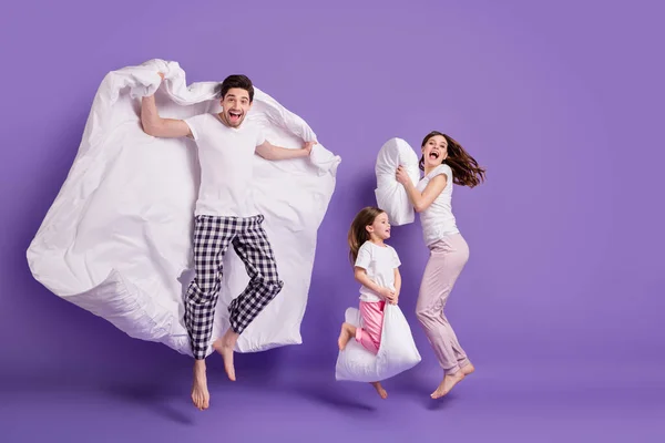 Full length body size view of cheerful cheery glad funny family small little daughter jumping pillow duvet having fun bedtime isolated on bright vivid shine vibrant violet color background