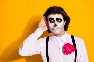 Photo of spooky zombie bristled guy hand ear interested overhear ghosts private conspiracy wear white shirt rose sugar skull death costume suspenders isolated yellow color background clipart