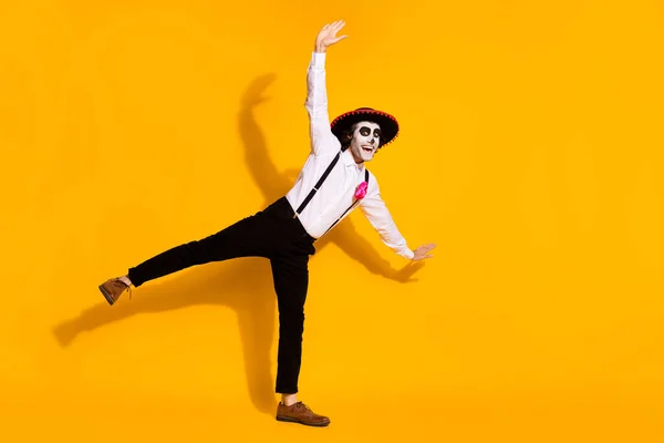 Plná délka fotografie strašidelný zombie chlap tanec předstírat létat letadlo póza festival zvýšit ruce vzrušený oblečení bílá košile růže smrt kostým sombrero podvazky izolované žlutá barva pozadí — Stock fotografie