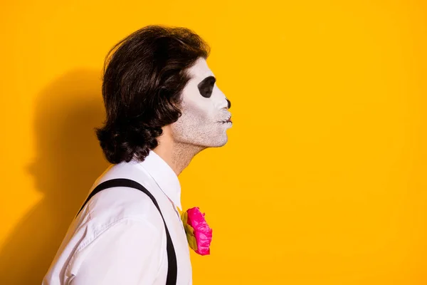 Closeup profile photo of creepy zombie dreamy guy empty space send air kiss bride corpse wear white shirt rose sugar skull death costume suspenders isolated yellow color background