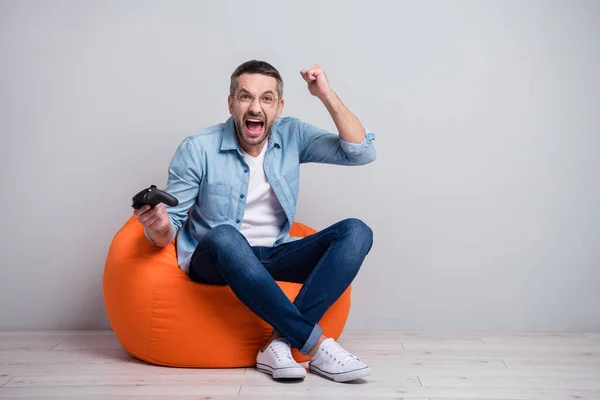 Retrato de su agradable atractivo alegre alegre loco de pelo gris chico sentado en la silla del bolso jugando juego en red divertirse regocijo aislado sobre gris luz pastel color fondo — Foto de Stock