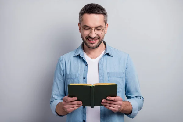 Close-up portrait of his he nice attractive cheerful cheery focused gray-haired guy reading interesting paper book isolated over gray light pastel color background