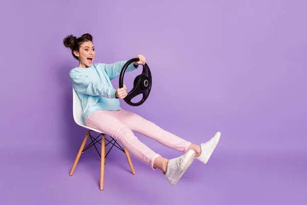她的画像她的容貌漂亮迷人有趣快乐快乐的女孩坐在椅子上手握方向盘，就像开汽车隔离在紫色淡紫色的淡紫色背景下 — 图库照片