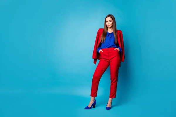 Foto de longitud completa de confianza en sí mismo bastante negocio señora mandona de pie de las manos en los bolsillos usan traje rojo blusa pantalones pantalones de tacón alto aislado de color azul de fondo —  Fotos de Stock