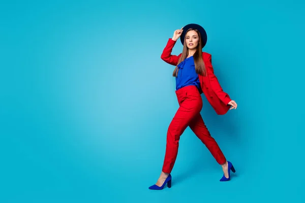 Photo complète du profil du corps de confiant joli patron femme d'affaires marchant dans la rue porter rétro casquette costume rouge blazer pantalon talons hauts isolé fond de couleur bleue — Photo