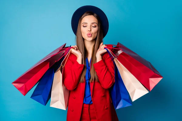 Foto von attraktiven Geschäftsfrau besuchen Einkaufszentrum mit vielen Packungen Senden Luftküsse tragen Retro-Kappe roten Anzug Bluse Hemd Blazer Hose isoliert blaue Farbe Hintergrund — Stockfoto