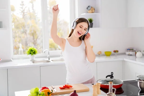 Foto van positieve vrolijke gastronomische meisje bereiden eco biologisch avondeten luisteren headset muziek genieten dans in keuken huis binnen — Stockfoto