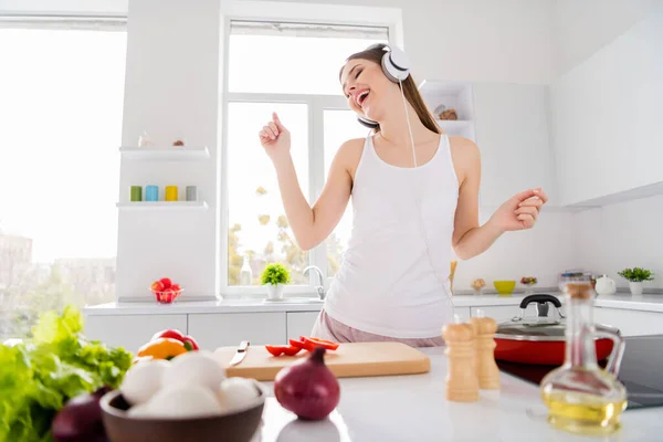 Foto van positieve vrolijke gastronomische chef-kok meisje bereiden verse biologische menu luisteren headset muziek dans in huis keuken binnen — Stockfoto