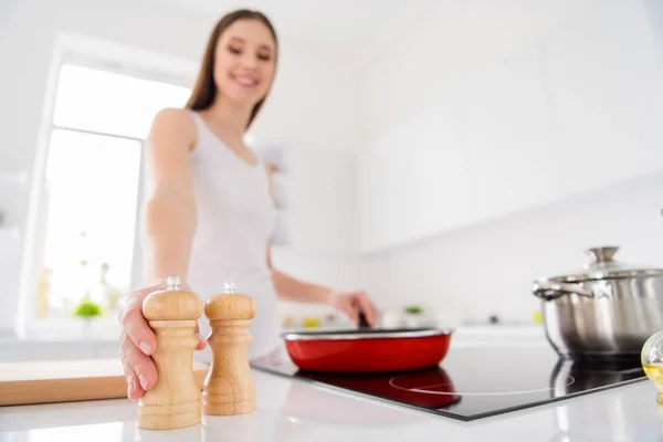 Image floue à angle bas du chef positif fille aux cheveux bruns frire végétarien petit déjeuner bio tenir sel choisir poivre pour une meilleure saveur dans la maison de cuisine à l'intérieur — Photo