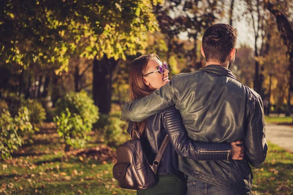 Back rear spine view photo of positive dream couple walk hug in fall september town center park hold backpack glasses — Stock Photo, Image