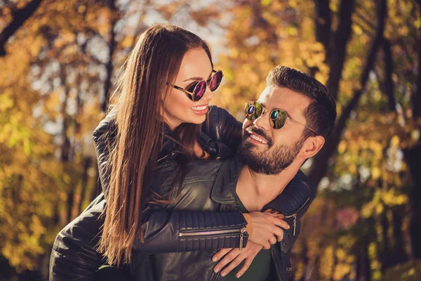 Foto von positiven Paar Kerl huckepack seine Freundin in September Stadt Sonnenschein Wald tragen lässig Jacken — Stockfoto