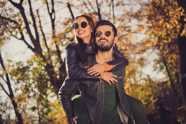 Foto de casal positivo cara segurar piggyback sua bela namorada em setembro cidade floresta parque desgaste jaqueta — Fotografia de Stock