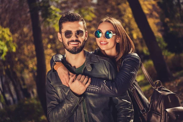 Foto de encantador casal positivo menina abraço piggyback seu namorado em setembro parque da cidade usar jaqueta casual — Fotografia de Stock