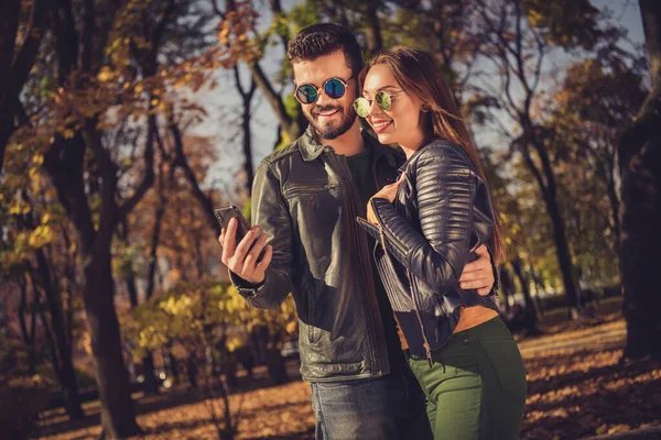 Photo of two people students guy girl read smartphone post in fall town october yellow forest park wear casual jacket — 스톡 사진