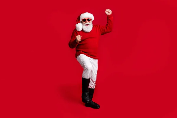 Foto de tamaño completo extático anciano jubilado pensionista santa claus headwear levantar los puños grito disfrutar de alegre acebo x-mas evento usar suéter pantalones botas aisladas brillo brillante color fondo —  Fotos de Stock