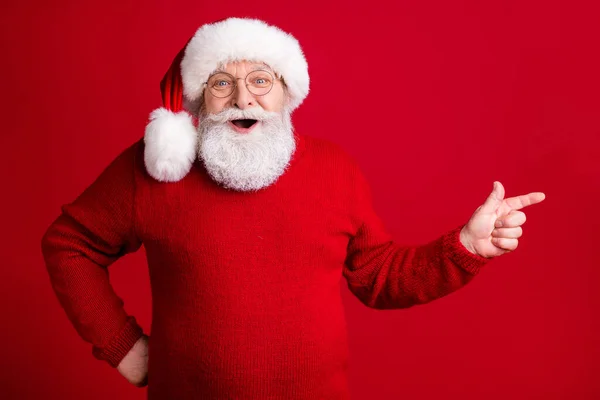 Foto van verbaasd oude man gepensioneerde gepensioneerde gepensioneerde in santa hoofdmode punt index vinger copyspace geven fee magie wonder advertenties x-mas promo slijtage jumper geïsoleerde heldere glans kleur achtergrond — Stockfoto