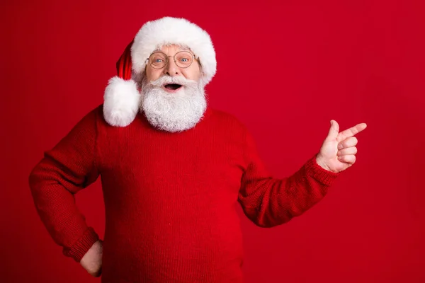 Erstaunt alter Mann Rentner in Santa Claus Kopfbedeckung Punkt Zeigefinger Copyspace x-mas Stechpalme Märchen lustige Wunder Werbung Förderung tragen Pullover isoliert helle Glanz Farbe Hintergrund — Stockfoto