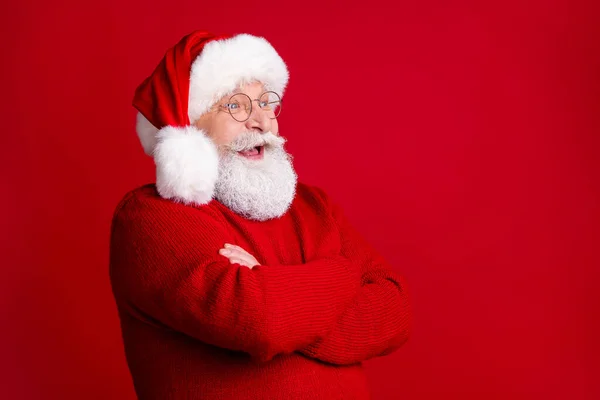 Profile side photo of positive excited old man in santa claus headwear cross hands enjoy rejoice x-mas holly jolly newyear event wear pullover isolated bright shine color background