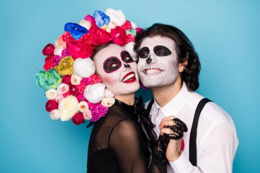 Profile photo of cute scary romantic couple man lady hold hands cuddle cheeks beaming smiling wear black dress death costume roses headband suspenders isolated blue color background clipart