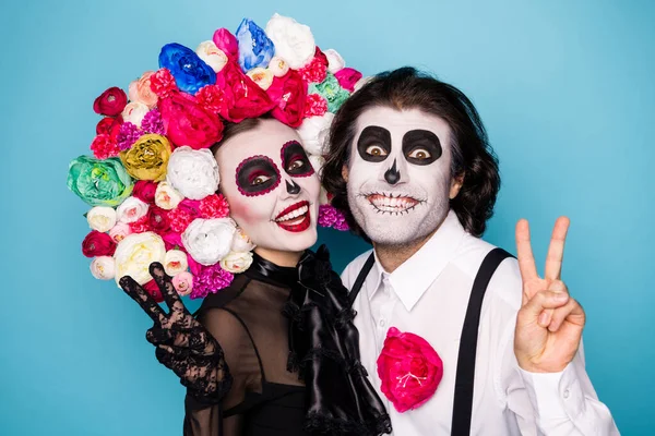 Photo of scary creepy couple man lady cuddle show v-sign make message picture living succesors wear black dress death costume mask rose headband suspender isolated blue color background