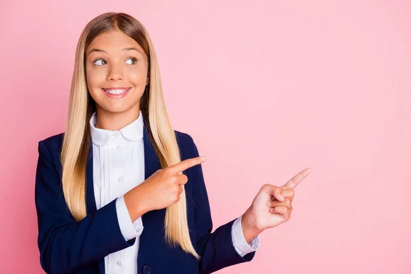 Kuva söpö viehättävä pieni nainen kiiltävä hymyilevä ohjaava sormet näyttävät tyhjä tila edistää koulun vaatteet myymälä kulumista yhtenäinen sininen takki valkoinen paita eristetty vaaleanpunainen väri tausta — kuvapankkivalokuva