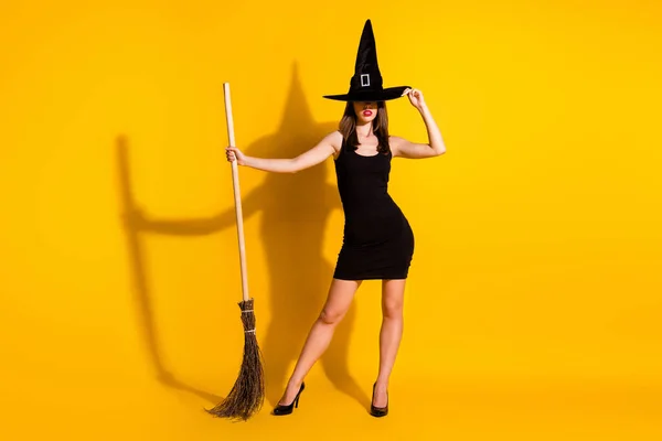 Full length body size view of her she nice attractive pretty slender thin creepy spooky lady wizard standing with broom posing isolated bright vivid shine vibrant yellow color background — Stock Photo, Image