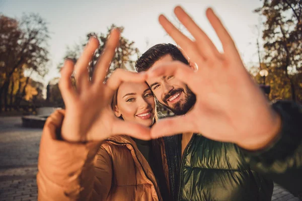 Portrait of bonding passionate couple girl guy make fingers heart in fall city center october park wear outerwear coats — Stock Photo, Image
