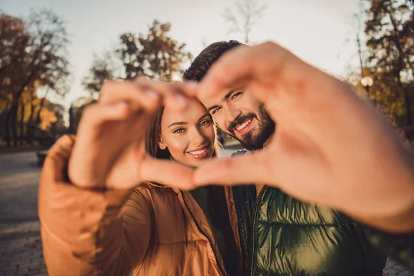 Retrato de encantador casal afetuoso fazer dedos coração no outono centro da cidade parque relaxar usar jaquetas de outubro — Fotografia de Stock