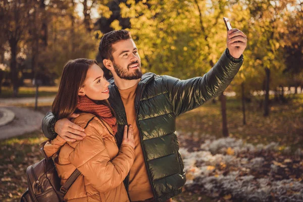 대학생 두 명이 여자 친구와 포옹하는 사진 가을 마을에서 스마트폰으로 셀카를 만들고 있다. — 스톡 사진