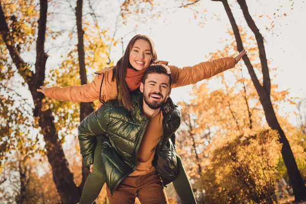 Low angle view photo of bonding couple man carry piggyback girl hand in autumn Σεπτέμβριος πάρκο πόλη φορούν παλτά — Φωτογραφία Αρχείου