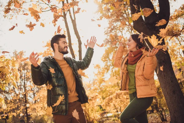 Pozitif neşe dolu bir çiftin fotoğrafı. Erkek adam Eylül 'de sarı yapraklar fırlatıyor. Açık havada şehir ormanlarında palto giyiyor. — Stok fotoğraf